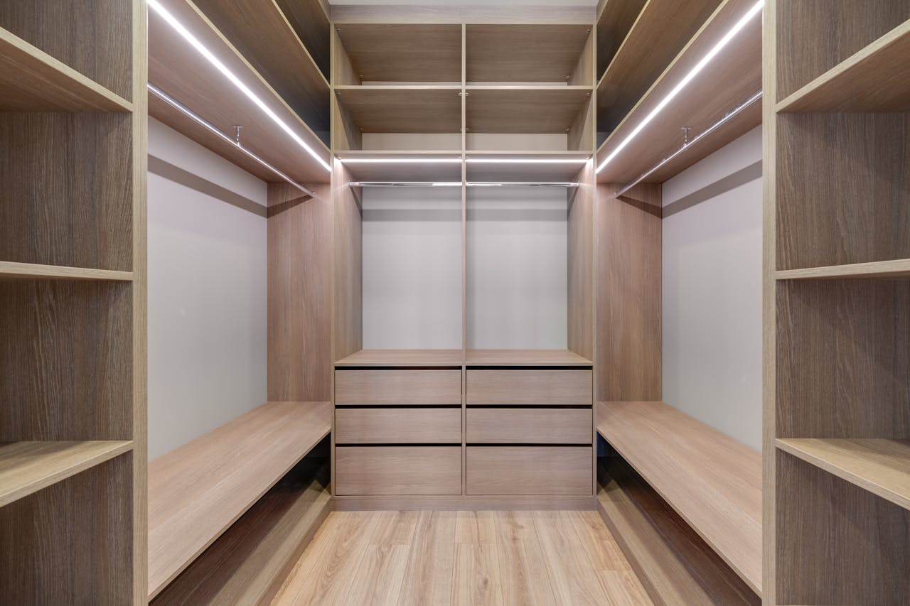 Home Spacious walk-in closet with wooden shelves and LED lighting creates a minimalist and modern design.